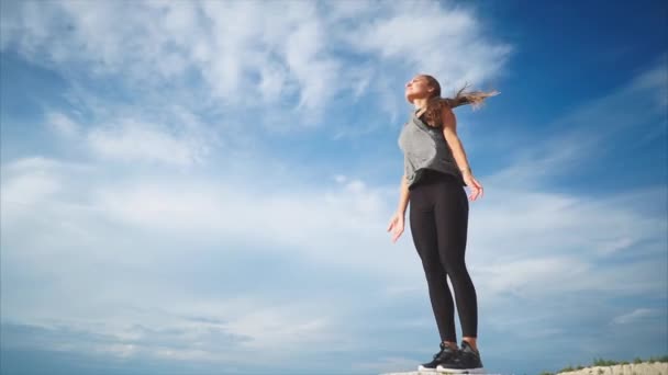 A young woman doing a solitary breathing exercise in nature fresh wind blows her — Stock Video