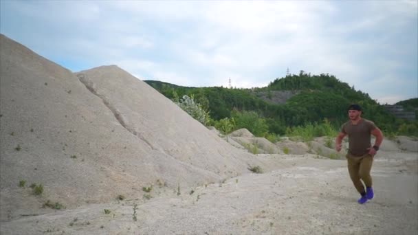 Ein sportlicher Mann läuft in der Natur, er übt am Sandstrand — Stockvideo