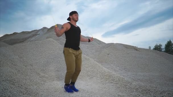 Genç adam aktif taş arka plan ile bir yaz gününde doğada ip atlama — Stok video