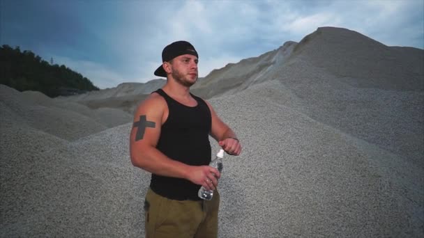 Ein Sportler trinkt unter freiem Himmel Mineralwasser aus einer Plastikflasche — Stockvideo