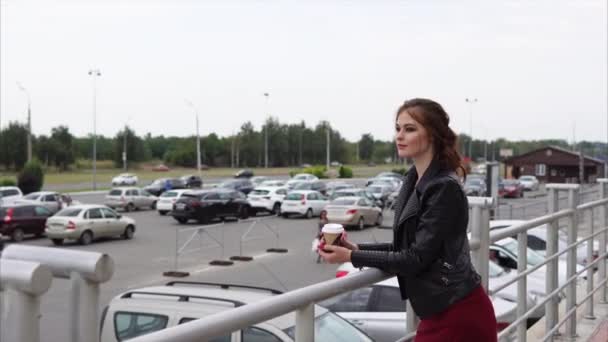 Lachende vrouw die kijkt naar een parkeerplaats houden een glas koffie weg te nemen — Stockvideo