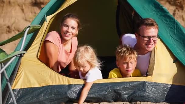 De familie die gelukkige dagen doorbrengen op het strand in tent echtgenoten en kinderen glimlachen — Stockvideo