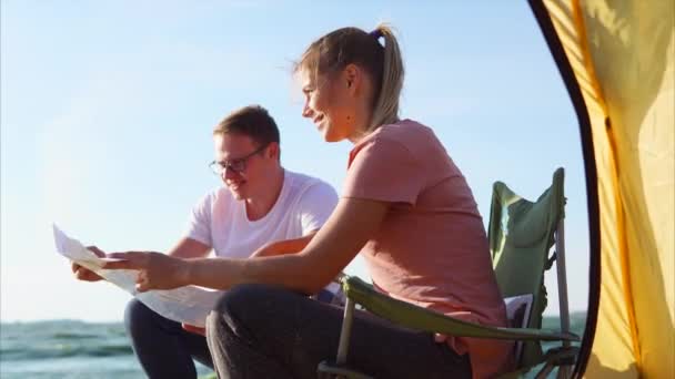 Una familia joven está considerando un mapa de camping para navegar por una ruta — Vídeos de Stock