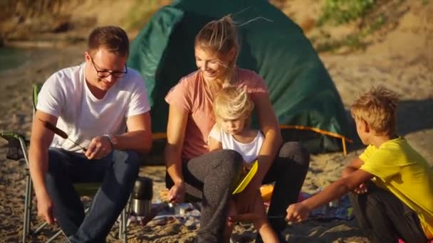 Couple affectueux de conjoints cuisiner des saucisses sur des brochettes sur le feu près de la tente un jour — Video
