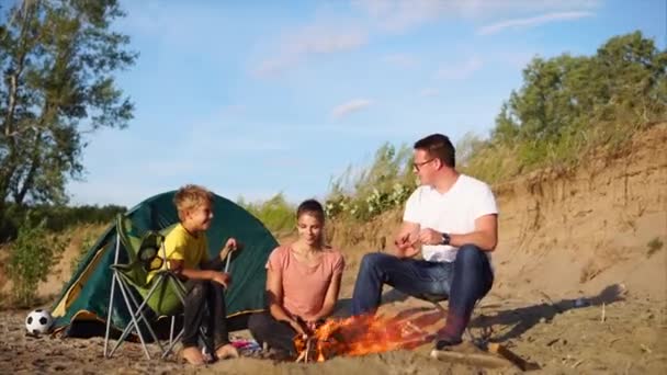 Una familia pasa el fin de semana en la zona de acampada cerca de la fogata al aire libre — Vídeos de Stock