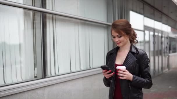 Menina com celular navegando nas mídias sociais e tomando café no caminho — Vídeo de Stock