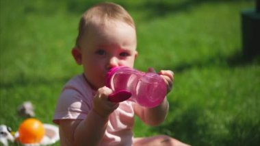 Küçük bir kız suyu bir çocuk plastik şişeden içer.