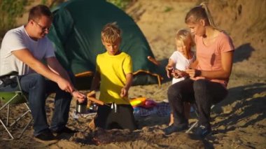 Ebeveynler ve çocuklar ateş üzerinde kamp yemek pişirme