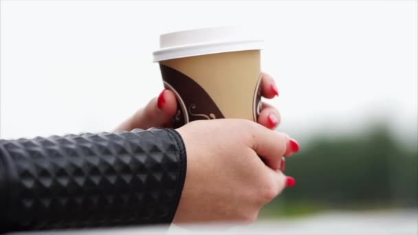 Mujer manos sosteniendo una taza de café caliente al aire libre — Vídeos de Stock