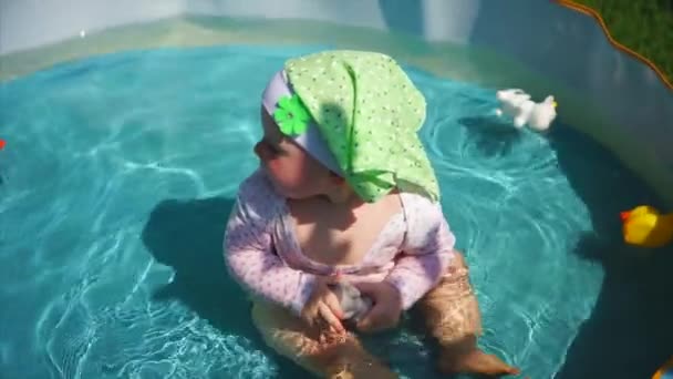 Feliz bebê menina tomando banho na piscina e brincando com brinquedos. Diversão da água no verão — Vídeo de Stock