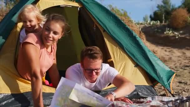 Una familia feliz y amigable hace un plan para la ruta de viaje en un mapa en papel — Vídeos de Stock