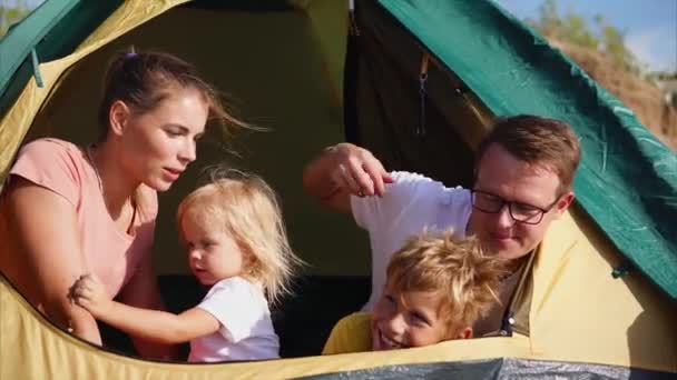 Ung familj som sitter i ett tält som titta på avståndet till natur människor är glada — Stockvideo
