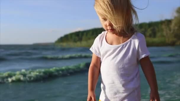 Roztomilá holčička pěšky podél břehu řeky. V jednotě s přírodou — Stock video