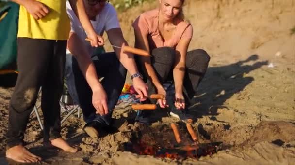 Син з батьками під час поїздки на вогонь обсмажують сосиски — стокове відео