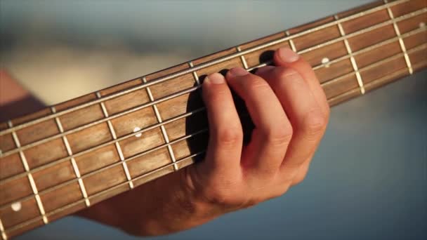 Close up tiro dos homens mãos, que classifica as cordas no painel da guitarra — Vídeo de Stock