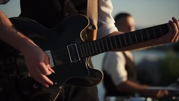 Nära upp skott av gitarren, en man spelar med hjälp av en medlare — Stockvideo