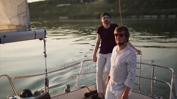 Dwóch przyjaciół, którzy są zaangażowani w żeglarstwie podziwiać zachód słońca w godzinach wieczornych — Wideo stockowe