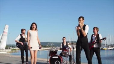 Bir yetişkin gençlik grup müzisyen gündüz denize yakın bir konser vermek