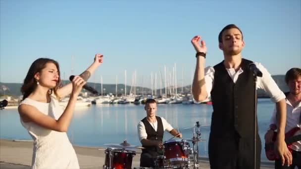 Молодые музыканты дают концерт своей группы на улице у моря — стоковое видео