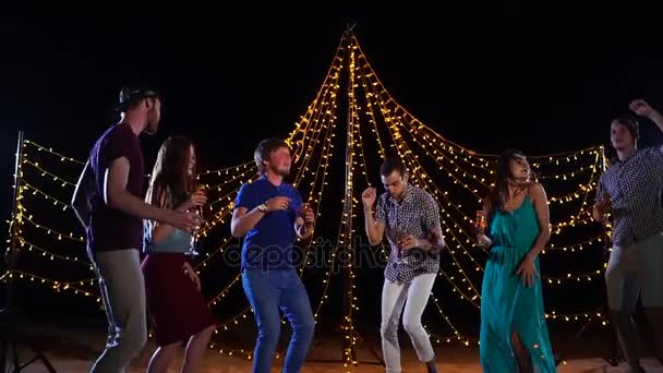 Jonge vrienden met glazen alcohol in hand dansen actief op een strand-disco — Stockvideo