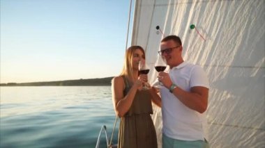 Güzel genç çift yaz aylarında gemiye kırmızı şarap içiyor.