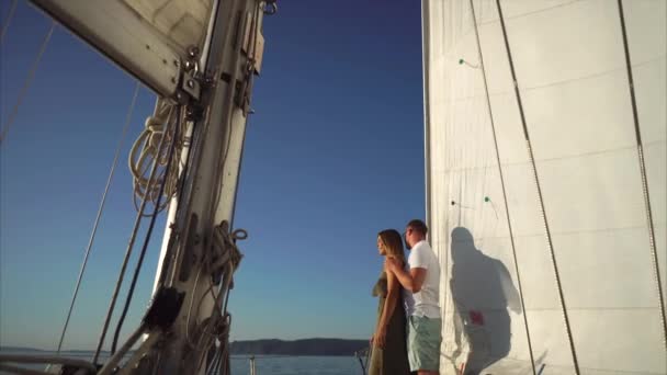 Man en vrouw zijn quitely kijken naar de zonsondergang aan boord van het jacht. — Stockvideo