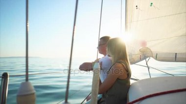 Genç adam ve kadın sarı saçlı bir yatta sakin güneşli bir günde oturuyor