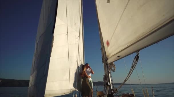 Kamera bewegt sich auf junges Liebespaar, das sich auf einem Segelboot umarmt. — Stockvideo