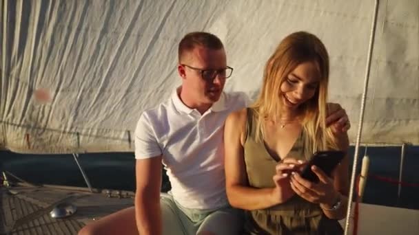 Jeune couple voyageant en yacht et utilisant un téléphone portable — Video