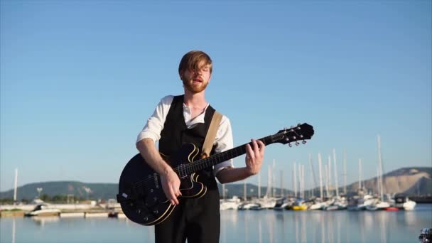 Joven músico tocando guitarra en solitario al aire libre — Vídeos de Stock
