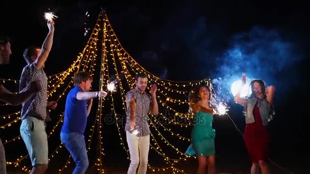 Friends dancing with sparklers during night beach party — Stock Video