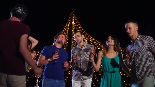 Grupo de amigos bailando y tomando bebidas en la fiesta al aire libre de noche — Vídeo de stock