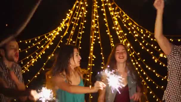 Glada vänner dansar med tomtebloss på natt fest — Stockvideo