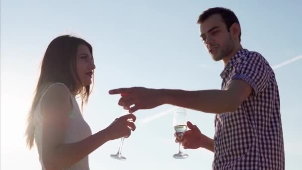 Casal jovem tomando bebidas no encontro. Cena contra o céu ao pôr do sol — Vídeo de Stock
