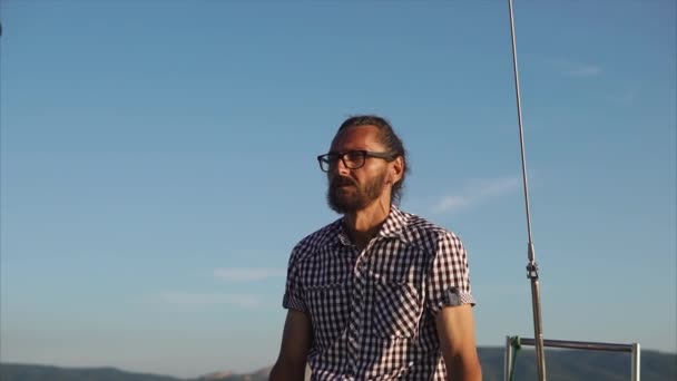 Hombre navegando un yate y mirando a su alrededor — Vídeo de stock