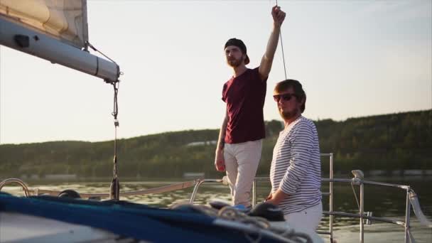 Två män vänner på båten vid solnedgången — Stockvideo