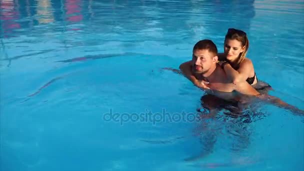 Pareja joven bañándose juntos en la piscina — Vídeo de stock