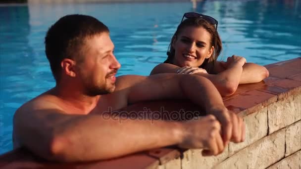 Casal jovem está nadando na piscina juntos . — Vídeo de Stock