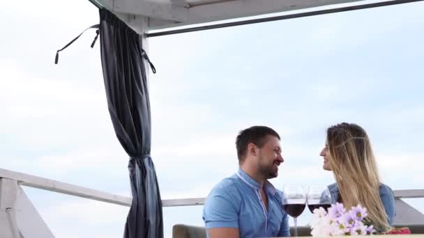 Hermosa pareja está sentada en la terraza junto al mar . — Vídeos de Stock