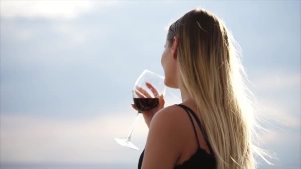 Une jeune femme boit du vin rouge dans un restaurant avec terrasse extérieure dans la nature — Video