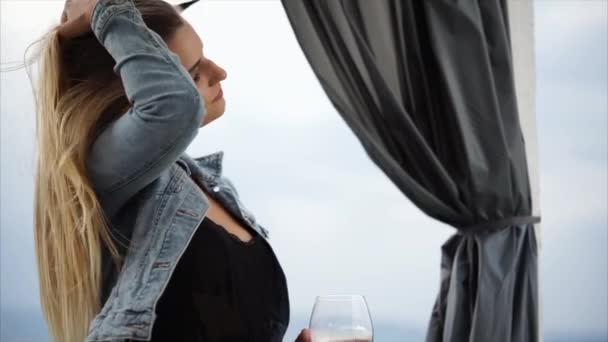 Regardez de près la belle femme qui boit du vin près de la mer . — Video