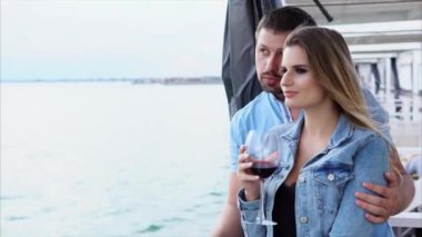 Bir adam bir kadeh şarap elinde tutan bir kadın hugs, onlar bir tekne yolculuğu