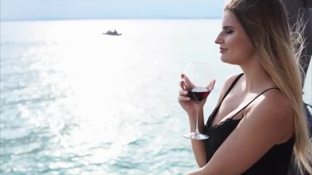 Μια νεαρή γυναίκα πίνει κρασί σε ένα εστιατόριο βάρκα, η οποία έχει μια ανοιχτή βεράντα — Αρχείο Βίντεο