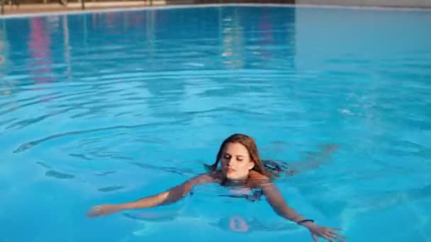 Mladá hezká blondýnka plavání v bazénu a pak ukazuje sexy tělo — Stock video