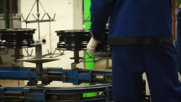 Worker put new-made rims on the conveyor belt. — Stock Video