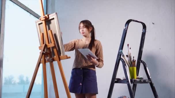 Fiatal gyönyörű lány a rajz egy beltéri festés. — Stock videók