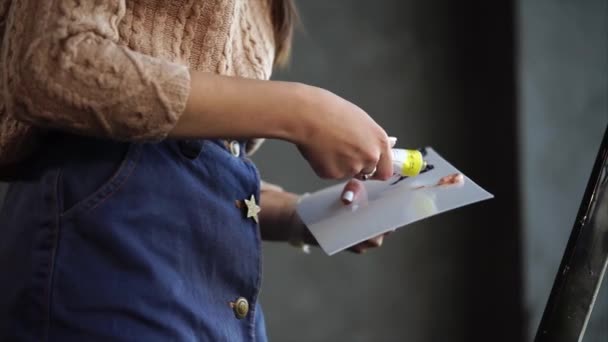 Jonge kunstenaar zet sommige verf op het stuk van karton. — Stockvideo