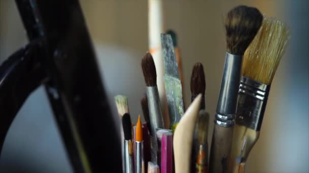 Close-up tiro de um copo com escovas de tamanhos diferentes, que pertencem ao artista — Vídeo de Stock