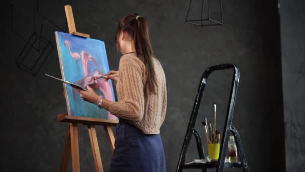 Una mujer dibuja flamencos en diferentes ángulos, en su mano hay una paleta con pintura — Vídeo de stock