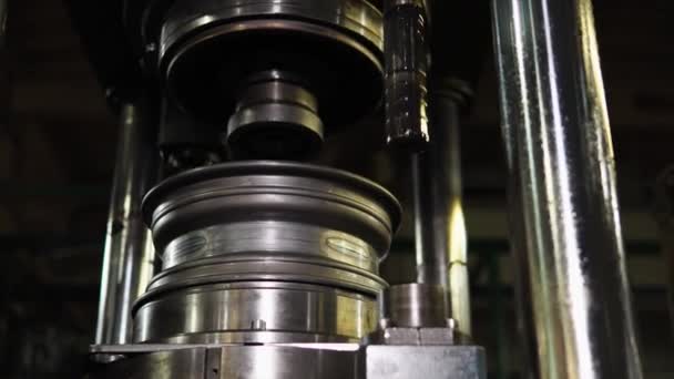 Worker is setting wheel rim under an automatic press to form the elements — Stock Video